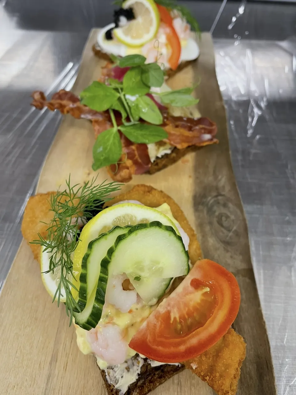 Tre stykker smørrebrød på en træplanke