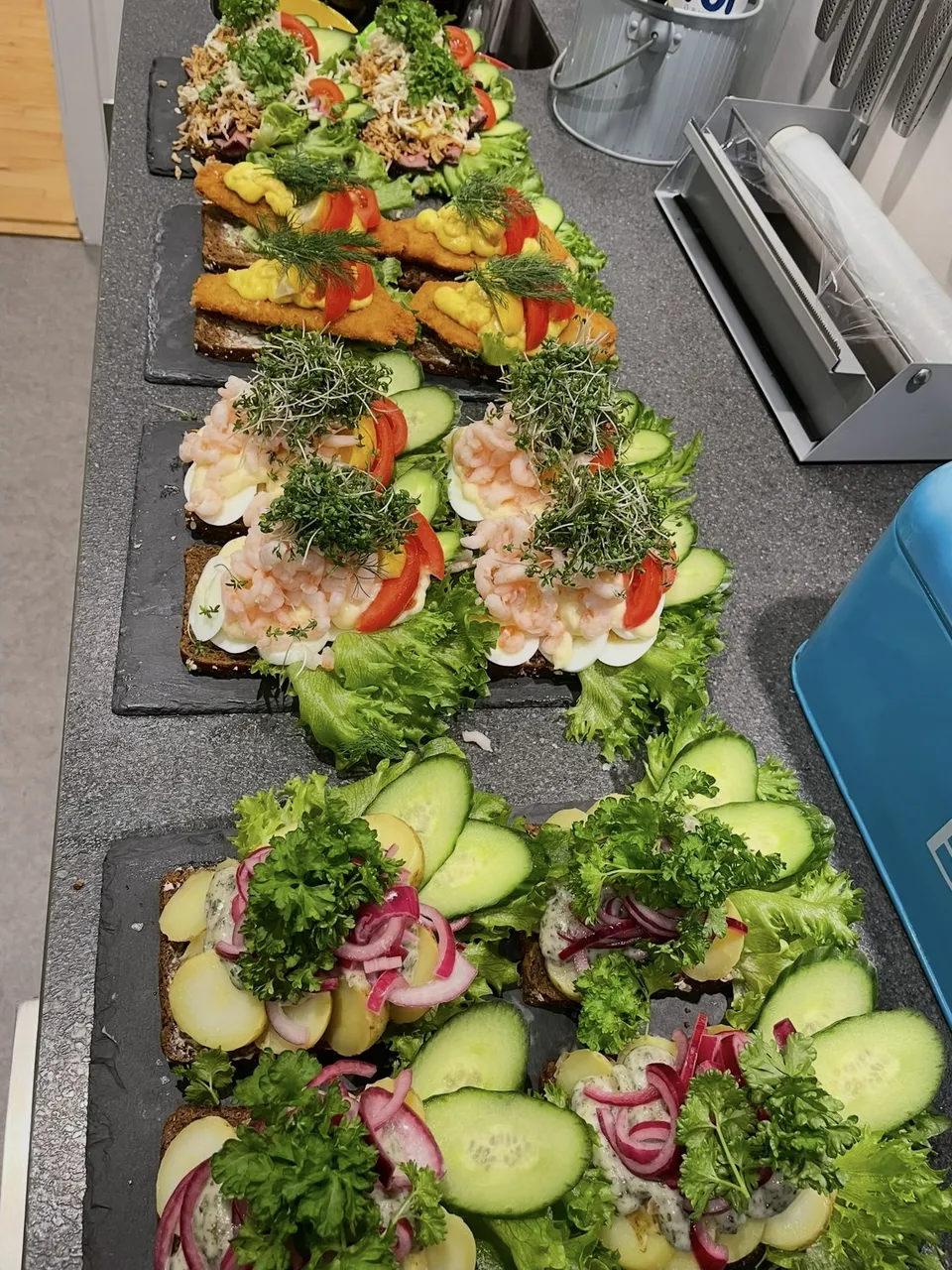 Lang række smørrebrød anrettet på skiferfade