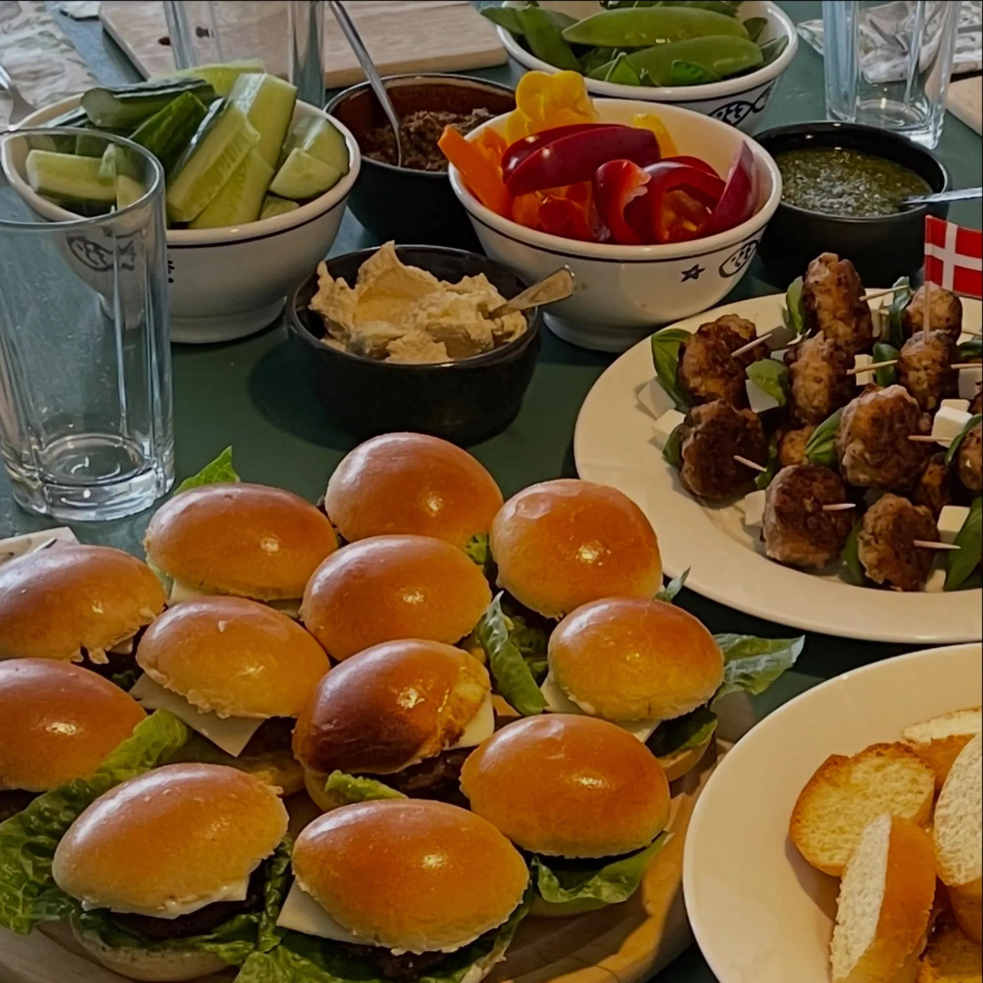 Bord med miniburgere, kødboller, dip, grøntsager og brød
